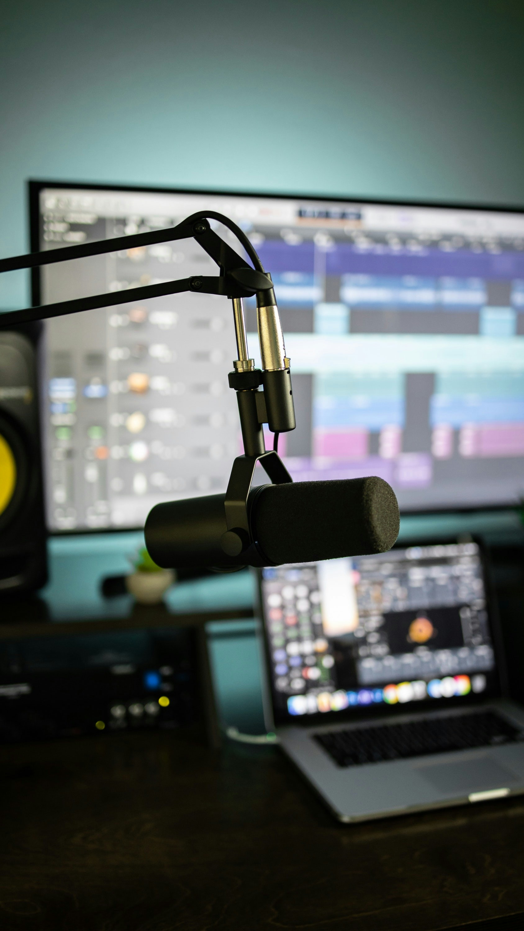 A microphone in front of a laptop showing the ElevenLabs AI voice generation interface with a waveform display