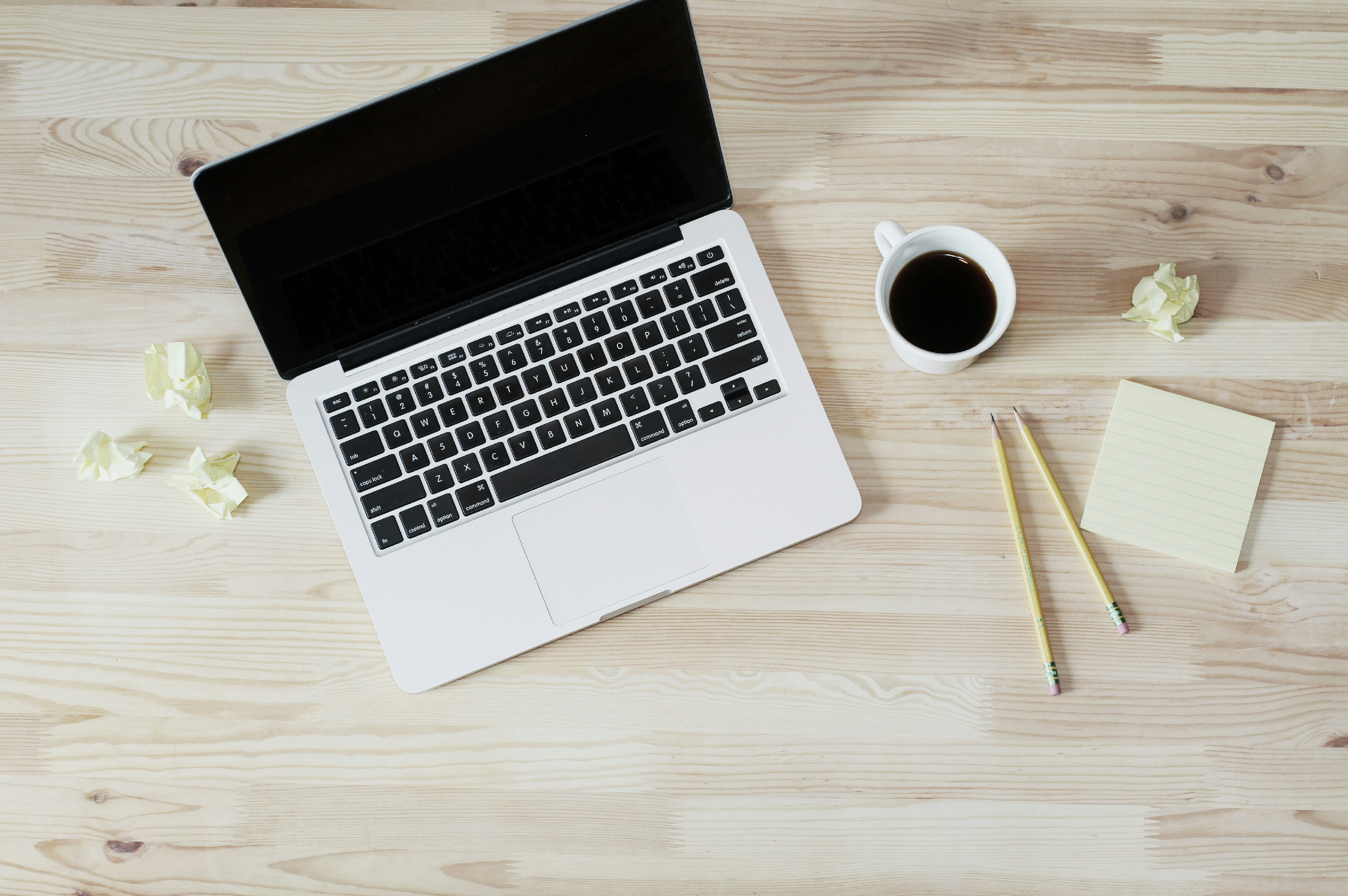 A clean, minimal desk setup with a laptop, notebook, and coffee cup representing a productive deep work session