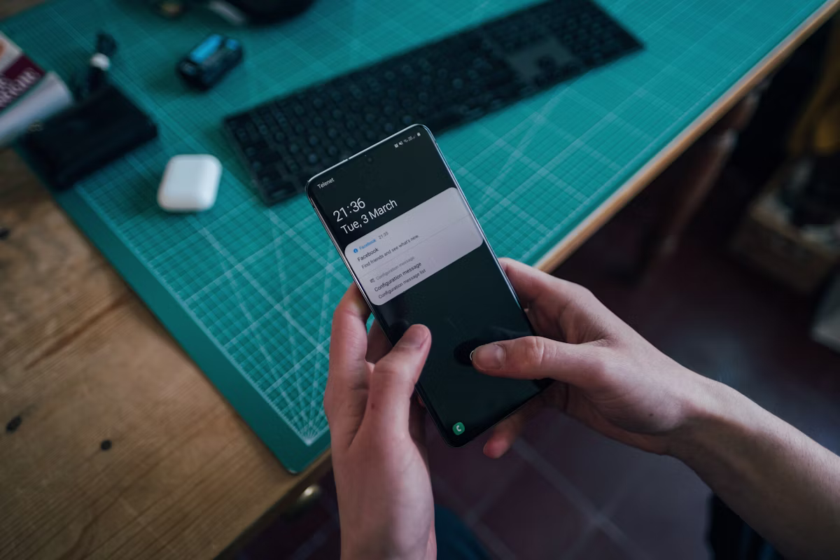 A person holding a black Android smartphone, looking closely at an incoming scam text message